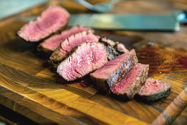 Beef filet mignon cooked to medium rare and sliced on a wooden cutting board, exposing the tender interior of this Certified ONYA® filet mignon 