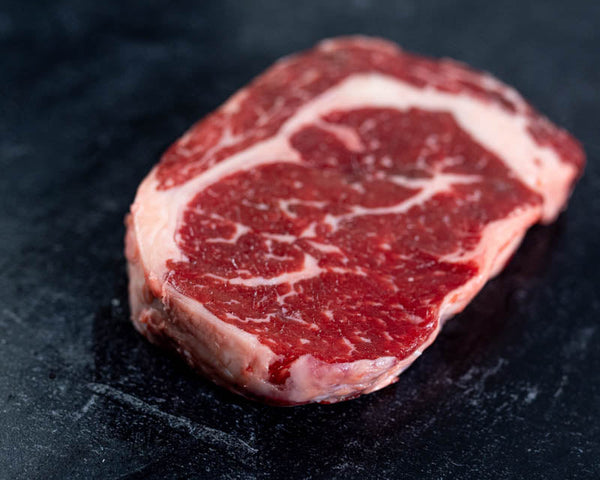 A side profile of a highly marbled Certified ONYA® beef rib eye steak from BetterFed Beef. This grain fed beef steak is 100% American beef available for sale online and shipped to your door